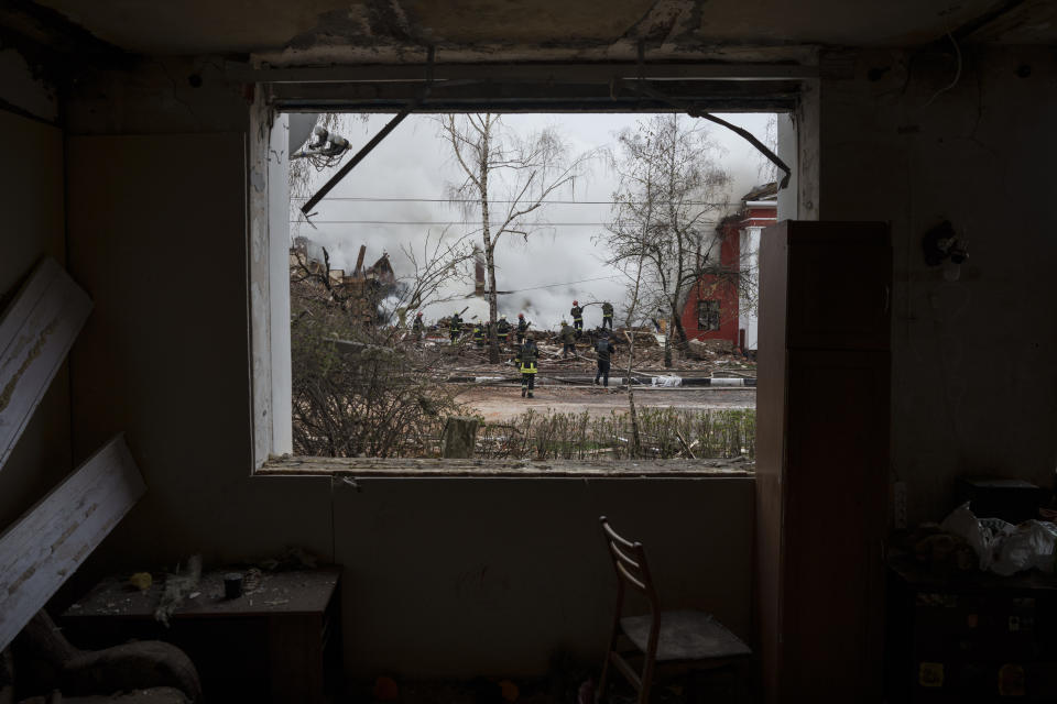 Firefighters are seen through the destroyed window of an apartment as they work to extinguish a fire after a Russian attack in Kharkiv, Ukraine, Tuesday, April 12, 2022. (AP Photo/Felipe Dana)
