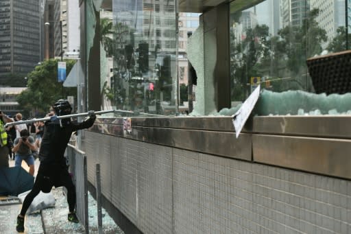 A hardcore Hong Kong protester uses a metal pole to smash glass outside an exit of the Central MTR underground metro station