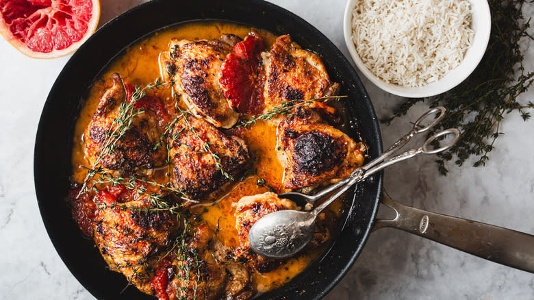 Chicken in pan with grapefruit and thyme beside rice