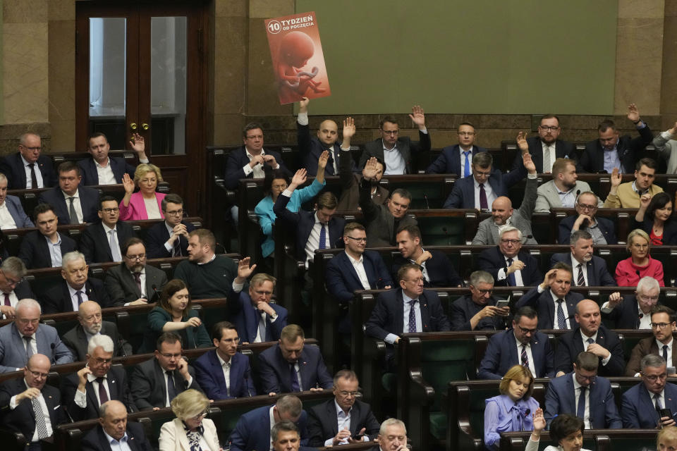 Dariusz Matecki, a conservative lawmaker in the Polish parliament, displays a poster showing a fetus and the words "10th week after conception," during a vote on abortion in Warsaw, Poland, on Friday, April 12, 2024. Polish lawmakers voted Friday to continue work on four proposals that would loosen the law on abortion, a divisive issue in the traditionally Roman Catholic country which has a near-total ban. (AP Photo/Czarek Sokolowski)