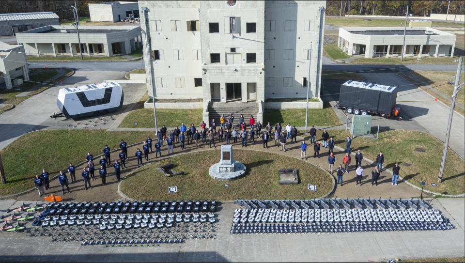 In this photo from the Defense Advanced Research Projects Agency, drones and participants in a Defense Department urban warfare exercise pose at Fort Campbell, Tenn., on Nov., 2021. A single operator supervised a swarm of more than 100 cheap, unscrewed air and land drones at the exercise. With tensions high over Taiwan, U.S. and Chinese military planners are readying themselves for a new kind of war where battleships, fighter jets and amphibious landings cede prevalence to squadrons of AI-enabled air and sea drones. (DARPA via AP)