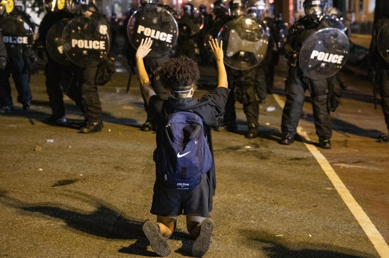 Black Lives Matter protests often pitted demonstrators against police − but not in every city. <a href="https://www.gettyimages.com/detail/news-photo/demonstrator-kneels-and-raises-her-hands-facing-a-police-news-photo/1216620688" rel="nofollow noopener" target="_blank" data-ylk="slk:Samuel Corum/AFP via Getty Images;elm:context_link;itc:0;sec:content-canvas" class="link ">Samuel Corum/AFP via Getty Images</a>