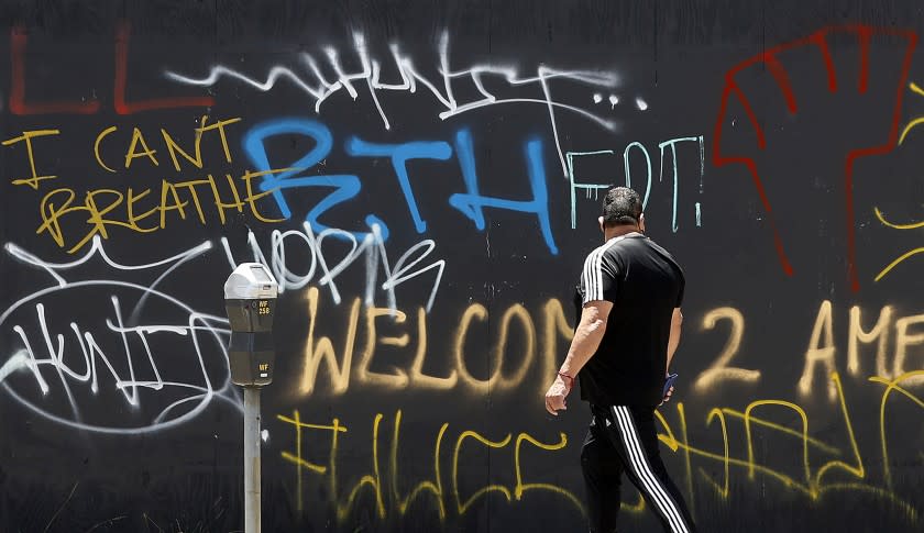 A pedestrian reads graffiti on 3rd Street in the Fairfax District on Sunday, May 31, 2020.