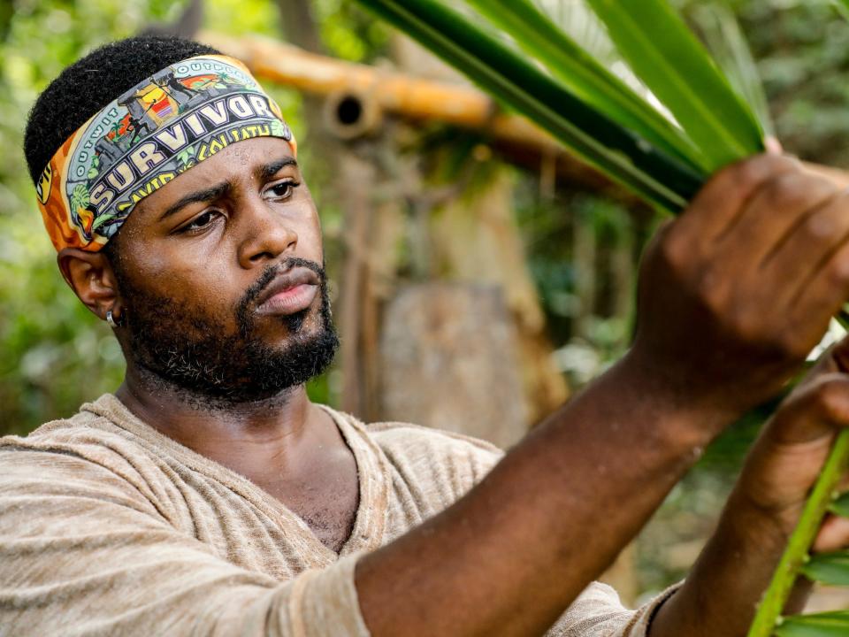 "Survivor" player Davie Rickenbacker holding leaves.