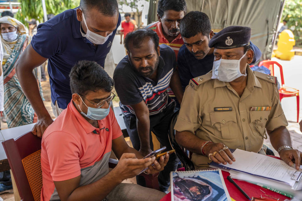 Relatives of victims of Friday's train accident try to identify their dear ones by looking at photographs on the phone of an official at the All India Institute of Medical Sciences hospital in Bhubaneswar in the eastern state of Orissa, India, Monday, June 5, 2023. Families of the victims of India’s deadliest train crash in decades filled the hospital on Monday to identify and collect bodies of relatives, as railway officials recommended the country’s premier criminal investigating agency to probe the crash that killed 275 people. (AP Photo/Rafiq Maqbool)