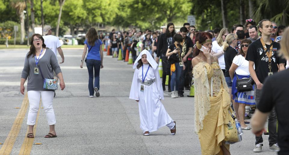 A Star Wars fan, with her daughter dressed as Princess Leia, reacts to seeing the line outside the Orange County Center, in Orlando, Fla., at the 2017 Star Wars Celebration, Thursday, April 13, 2017, marking the 40th anniversary of the original 1977 Star Wars film. Thousands of fans waited for hours in the line, estimated to be more than a mile long, to access the convention. (Joe Burbank/Orlando Sentinel via AP)