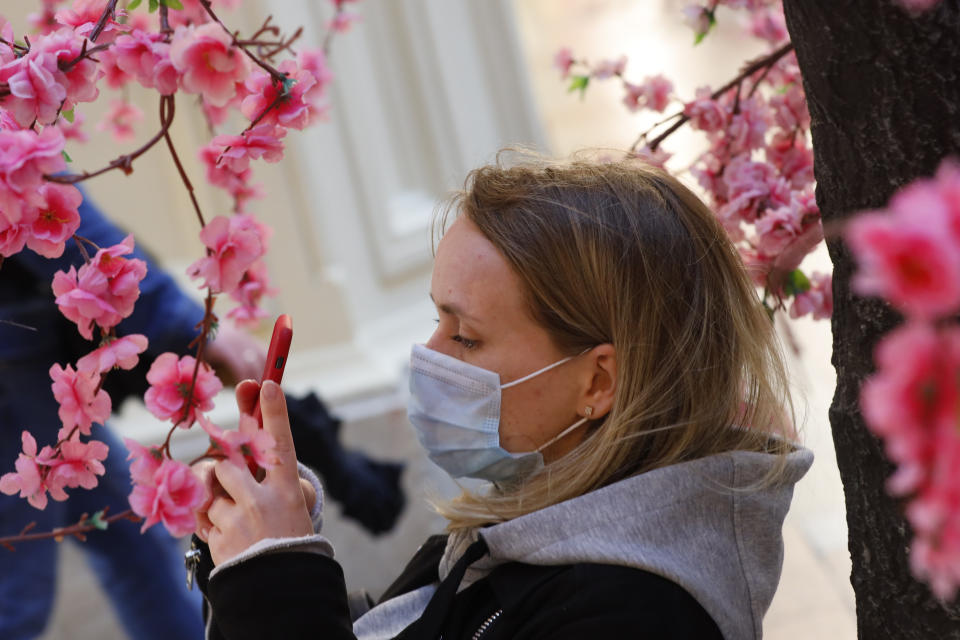 A woman wearing a face mask to help curb the spread of the coronavirus takes photo of fake flowers at the GUM, the State Department store, near Red Square in Moscow, Russia, Thursday, June 10, 2021. The Russian authorities reported a spike in coronavirus infections on Thursday, with new confirmed cases exceeding 11,000 for the first time since March. (AP Photo/Alexander Zemlianichenko)