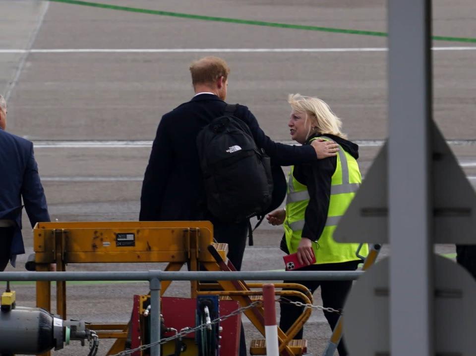 El príncipe Harry estuvo acompañado por una mujer que vestía un chaleco de alta visibilidad, con quien habló y en un momento colocó su mano sobre su hombro (Peter Summers/Getty Images)