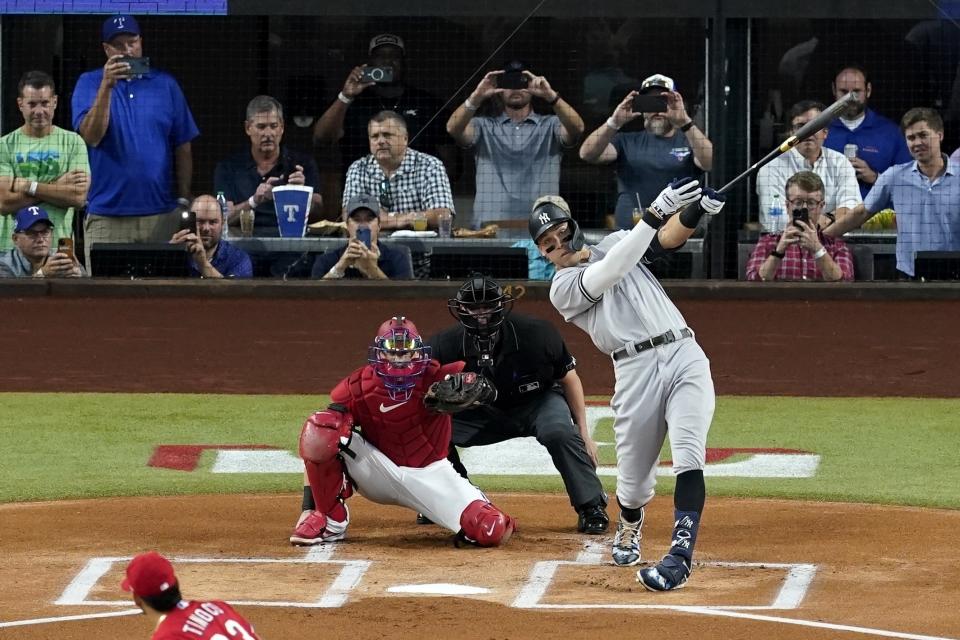 FILE- New York Yankees' Aaron Judge connects for a solo home run, his 62nd of the season, off of Texas Rangers starting pitcher Jesus Tinoco as Texas Rangers catcher Sam Huff and umpire Randy Rosenberg look on in the first inning of the second baseball game of a doubleheader in Arlington, Texas, Oct. 4, 2022. (AP Photo/Tony Gutierrez, File)