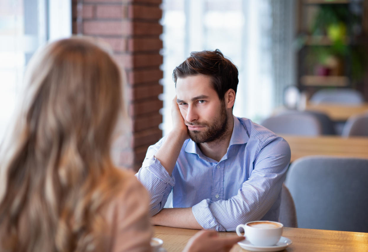 Young guy feeling bored on dull date at restaurant, disappointed in his partner. Millennial couple having disagreement, cannot find common grounds. Relationship problem concept