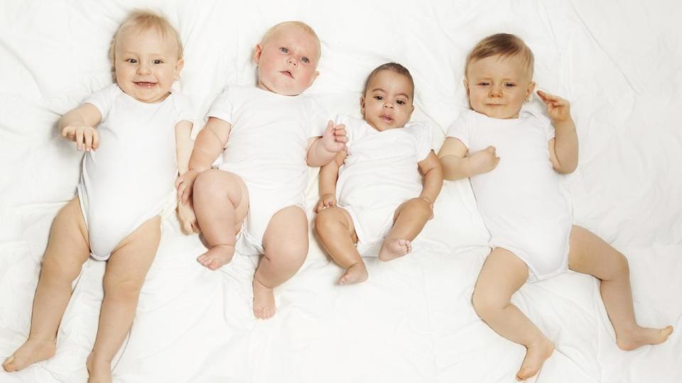 Four babies lay in a row on the white background