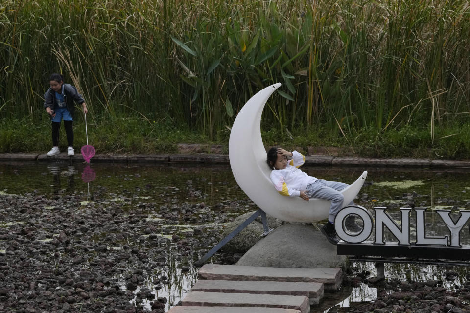 Children play at a pond and plants at the "Fish Tail" sponge park built on a former coal ash dump site in Nanchang in north-central China's Jiangxi province on Saturday, Oct. 29, 2022. The concept of the park involves creating and expanding parks and ponds within urban areas to prevent flooding and absorb water for times of drought. (AP Photo/Ng Han Guan)