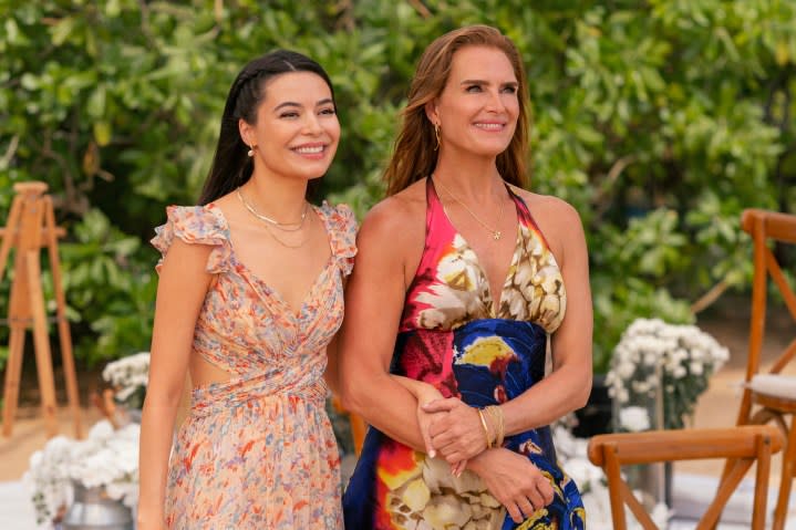 A mother and daughter stand next to each other and smile.