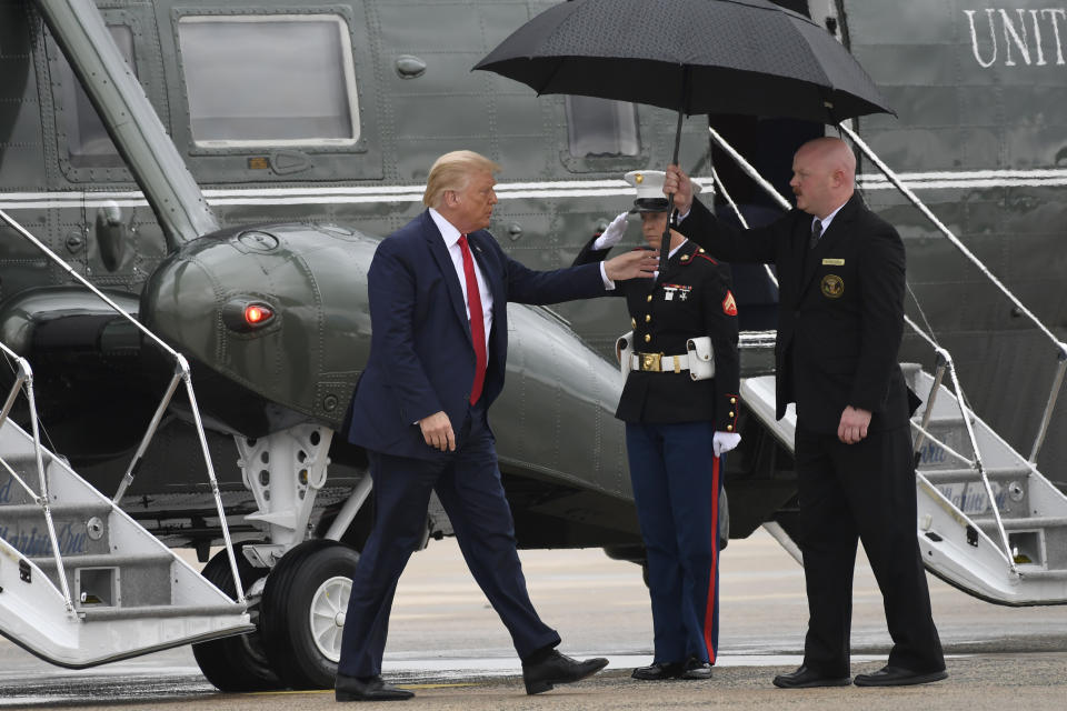 President Donald Trump is handed an umbrella as he steps off of Marine One and heads toward Air Force One at Andrews Air Force Base in Md., Friday, July 31, 2020. Trump is en route to Florida for events.. (AP Photo/Susan Walsh)