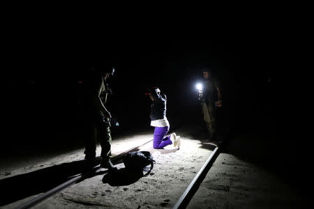 Migrant Yoniel Torres, 31, from Cuba is handcuffed after being detained by the police by a train line in a mined area of desert at the Chilean and Peruvian border in Arica, Chile, November 14, 2018. "A coyote (people trafficker) left me near (Peruvian border town) Tacna and told me to follow the old railway line," Torres said. "This is all horrible. The journey was so hard. I just came in search of a better life." REUTERS/Ivan Alvarado