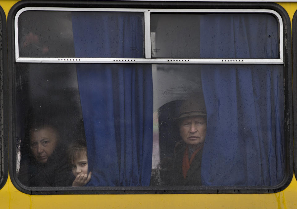 FILE - In this Friday, March 7, 2014 file photo, people in a passing bus watch a rally against the breakup of the country in Simferopol, Ukraine. Despite the pebble beaches and cliff-hung castles that made Ukraine’s region of Crimea famous as a Soviet resort hub, the peninsula has long been a corruption-riddled backwater in economic terms. The Kremlin, which has moved to annex the region after its residents voted in a referendum on Sunday to join Russia, has begun calculating exactly what it will cost to support the region’s shambolic economy - which one Russian minister described as “no better than Palestine.” (AP Photo/Vadim Ghirda, File)