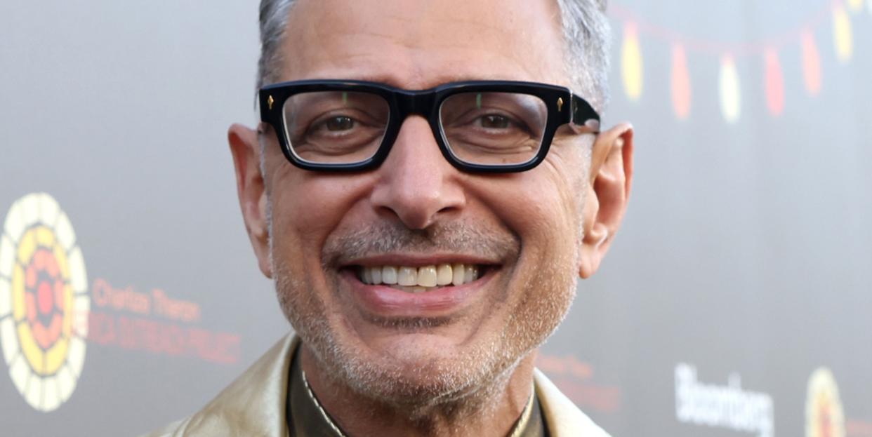 jeff goldblum smiling, gold suit, gold shirt, glasses,