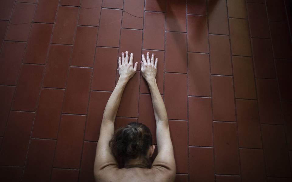 Carolina Wolf, who dances with Venezuela's national ballet, stretches in her living room at the end of a training session, during a lockdown to curb the spread of COVID-19 in Caracas, Venezuela, Tuesday, Aug. 11, 2020. The 42-year-old ballerina said her living room is four times smaller than the studio where she practiced daily at the famed Teresa Carreño Theater, and she doesn't dare do jumps in fear of injuring herself on the hard floor. (AP Photo/Ariana Cubillos)