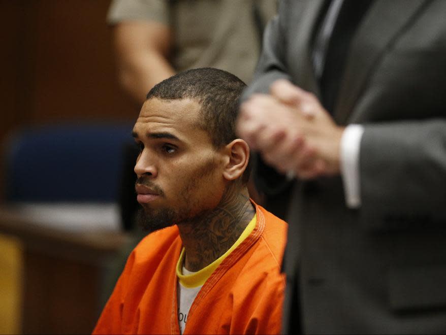 R&B singer Chris Brown, center, appears in Los Angeles Superior Court with his attorney Mark Geragos, right, on Monday, March 17, 2014. Brown will spend another month in jail after a judge said Monday he was told the singer made troubling comments in rehab about being good at using guns and knives. The singer was arrested on Friday, March 14, 2014, after he was dismissed from a Malibu facility where he was receiving treatment for anger management, substance abuse and issues related to bipolar disorder. (AP Photo/Lucy Nicholson, Pool)