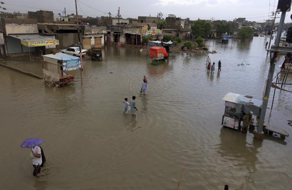 Local residents wade through flooded area caused by heavy monsoon rains, in Karachi, Pakistan, Friday, Aug. 28, 2020. Heavy rains hit Pakistan's financial capital Karachi for a fifth straight night, bringing more flooding and killing some more people, officials said, as rescuers evacuated people from flooded neighborhoods. (AP Photo/Fareed Khan)