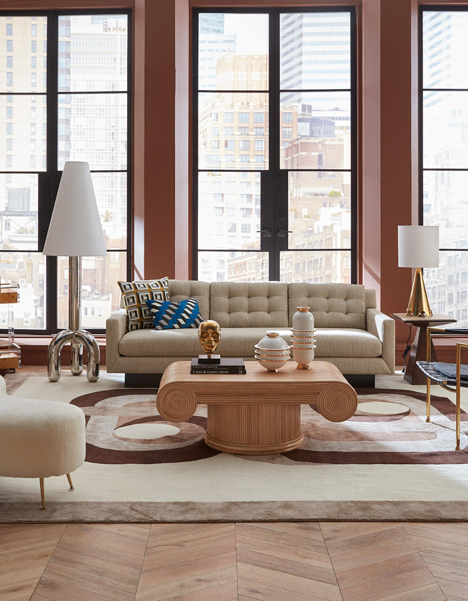 Studded cream sofa, large neutral rug, shapely coffee table and floor lamp
