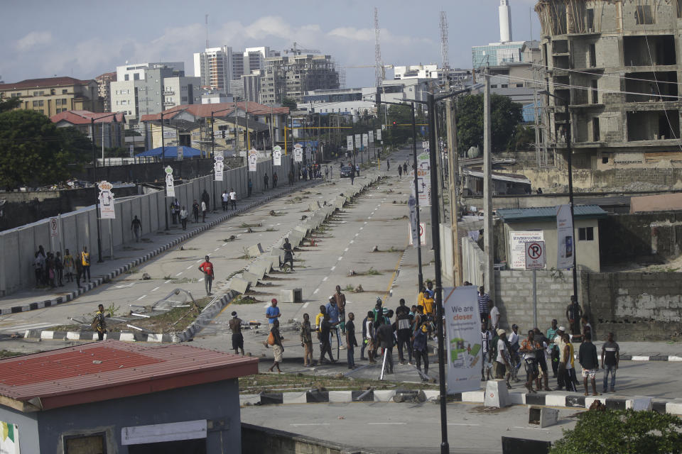 Protesters run away as police officers use teargas to disperse groups of demonstrating against police brutality in Lagos, Nigeria, Wednesday Oct. 21, 2020. After 13 days of protests against alleged police brutality, authorities have imposed a 24-hour curfew in Lagos, Nigeria's largest city, as moves are made to stop growing violence. ( AP Photo/Sunday Alamba)