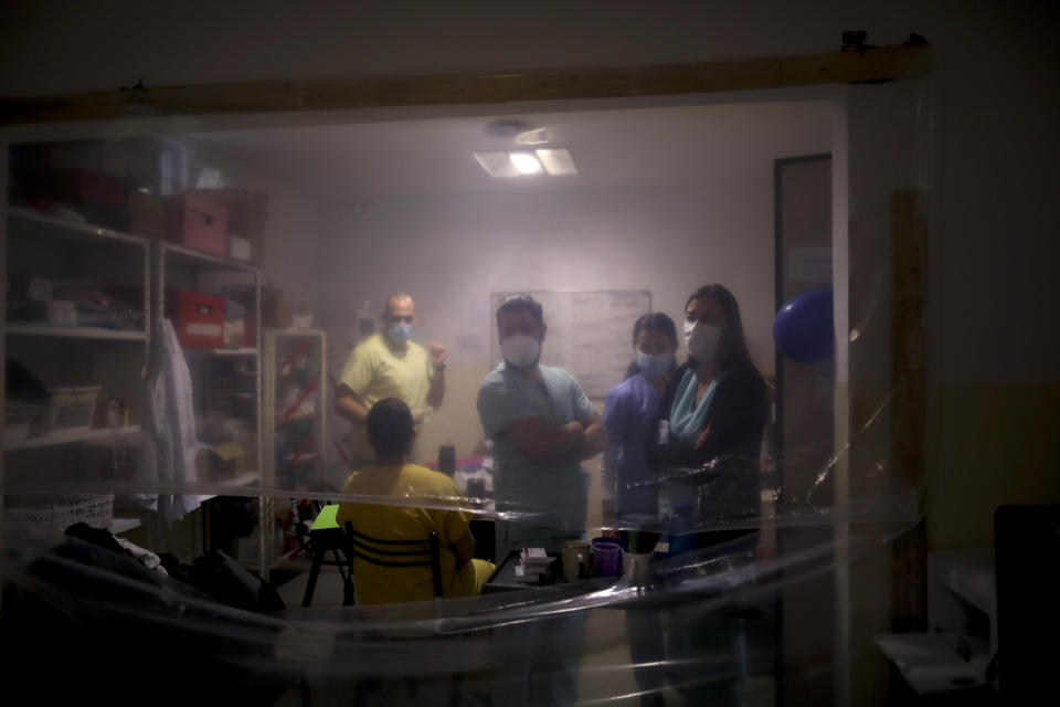 FILE - In this July 14, 2020 file photo, health care providers gather inside a work area protected by a sheet of plastic at the Eurnekian Ezeiza Hospital on the outskirts of Buenos Aires, Argentina, during a government-ordered lockdown to curb the spread of the new coronavirus. Argentina reached 1 million confirmed coronavirus cases on Monday, Oct. 19, 2020, according to the Ministry of Health. (AP Photo/Natacha Pisarenko, File)