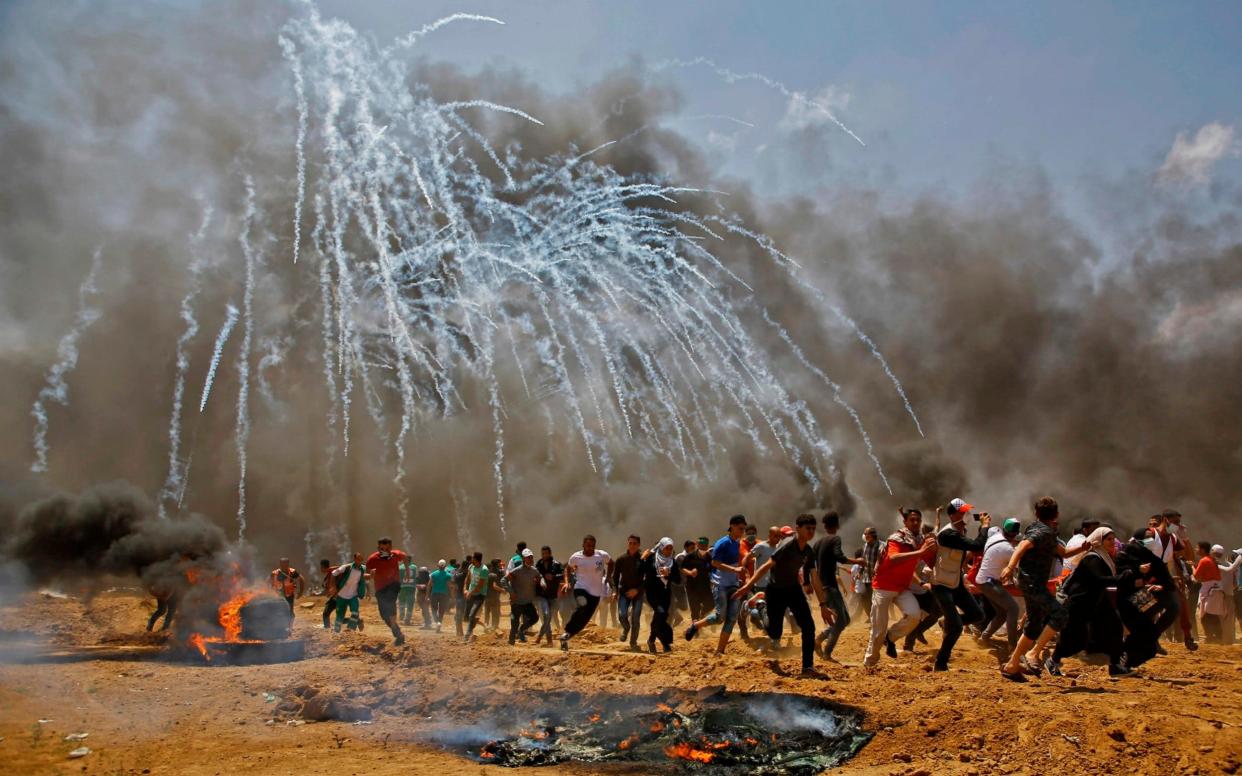 Palestinians run for cover as tear gas rains down near the border between Israel and the Gaza Strip - AFP