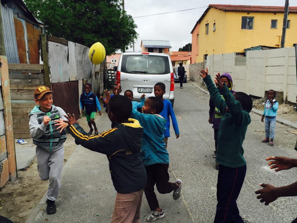 A group of kids playing with a ball in the street.