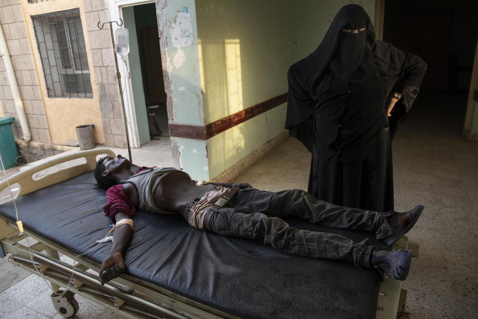 In this Aug. 1, 2019 photo, an Ethiopian Tigray migrant who was imprisoned by traffickers for months, lies on a gurney accompanied by a nurse at the Ras al-Ara Hospital in Lahj, Yemen. Nurses gave him fluids but he died several hours later. (AP Photo/Nariman El-Mofty)