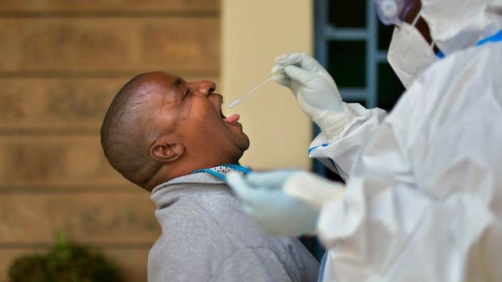 A man reacts before receiving a throat swab administered by a public health official wearing personal protective equipment (PPE) at a site for mass testing for the COVID-19 coronavirus in Ruaraka, a densely populated suburb in Nairobi on May 28