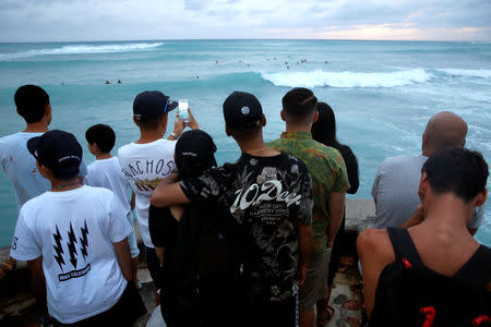 Tourists watch surfers in Waikiki Bay as Tropical Storm Lane approaches Honolulu, Hawaii, U.S. August 24, 2018. REUTERS/Terray Sylvester