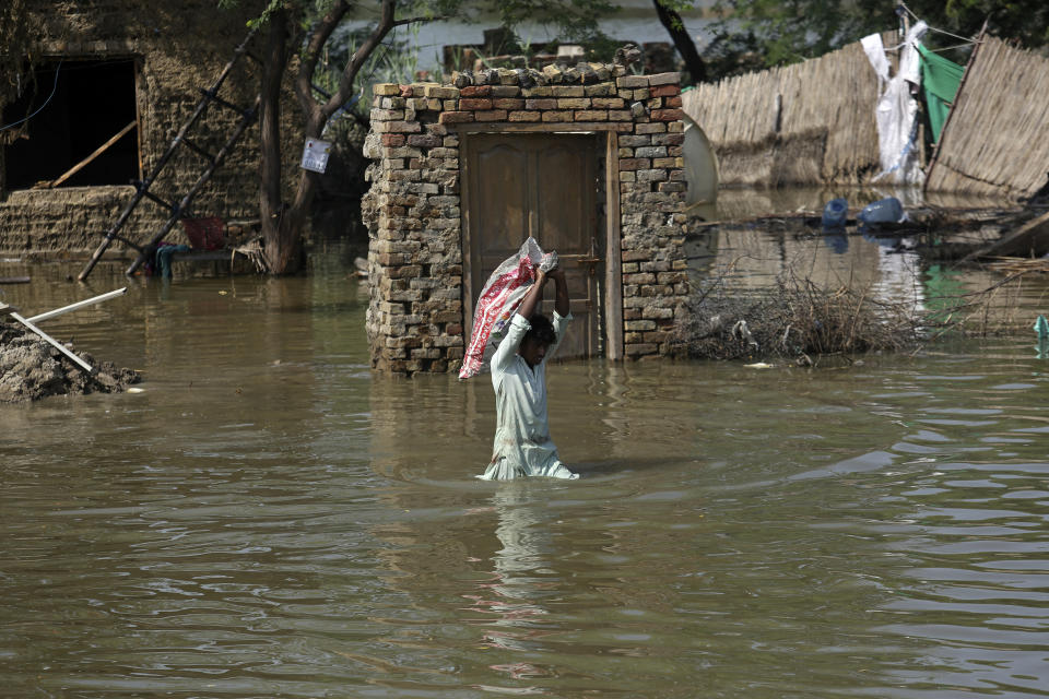 FILE - A man carries usable belongings salvaged from his flood-hit home across a flooded area in Shikarpur district of Sindh province, of Pakistan, Wednesday, Aug. 31, 2022. The U.N. weather agency is predicting the phenomenon known as La Nina is poised to last through the end of this year, a mysterious “triple dip” — the first this century — caused by three straight years of its effect on climate patterns like drought and flooding worldwide. (AP Photo/Fareed Khan, File)