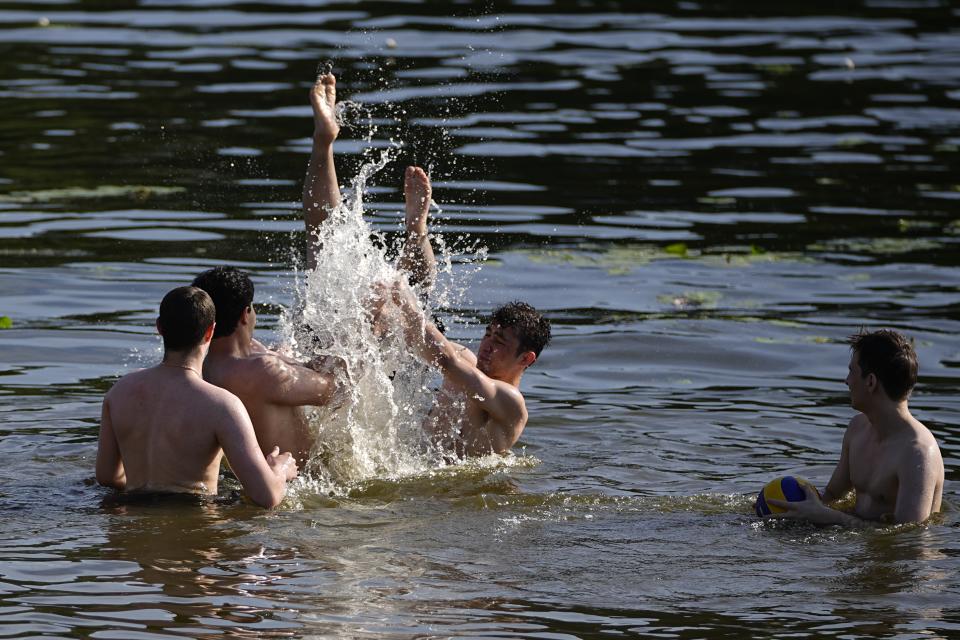 Men play in the Moskva river at Serebryany Bor park in Moscow, Russia, Thursday, July 11, 2024. Warm weather has settled in Moscow with a temperature of 30 Celsius, (86 Fahrenheit) and will increase in the coming days. (AP Photo/Pavel Bednyakov)