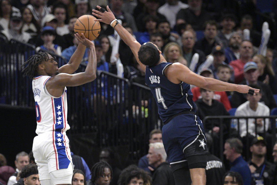 Philadelphia 76ers guard Tyrese Maxey (0) shoots a 3-pointer as Orlando Magic guard Jalen Suggs (4) defends during the second half of an NBA basketball game, Wednesday, Dec. 27, 2023, in Orlando, Fla. (AP Photo/Phelan M. Ebenhack)