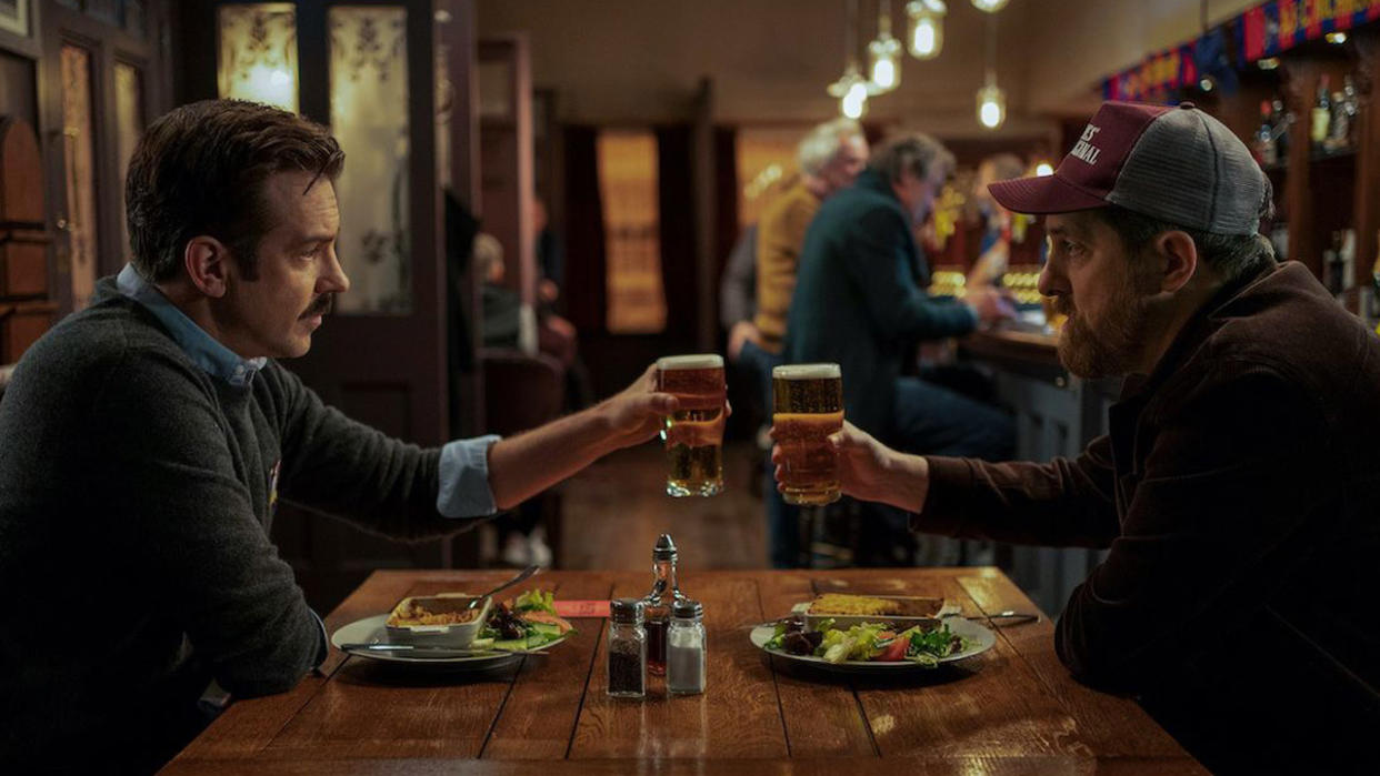  Jason Sudeikis as Ted and Brendan Hunt as Coach Beard toasting pints in the pub 