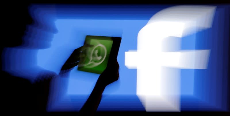 FILE PHOTO: Woman holds a tablet displaying WhatsApp's logo in front of the screen with the Facebook logo in this photo illustration taken in Prague