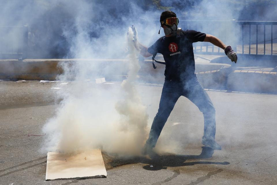 An anti-government protester throws a teargas canister back at the police in Caracas