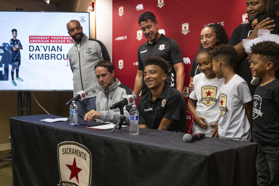 Da'vian Kimbrough, 13, is surrounded by his family and team management after signing contract with the Sacramento Republic of the second-tier League Championship of the United Soccer League, Tuesday, Aug. 8, 2023, in Sacramento, Calif. (Paul Kitagaki Jr./The Sacramento Bee via AP)