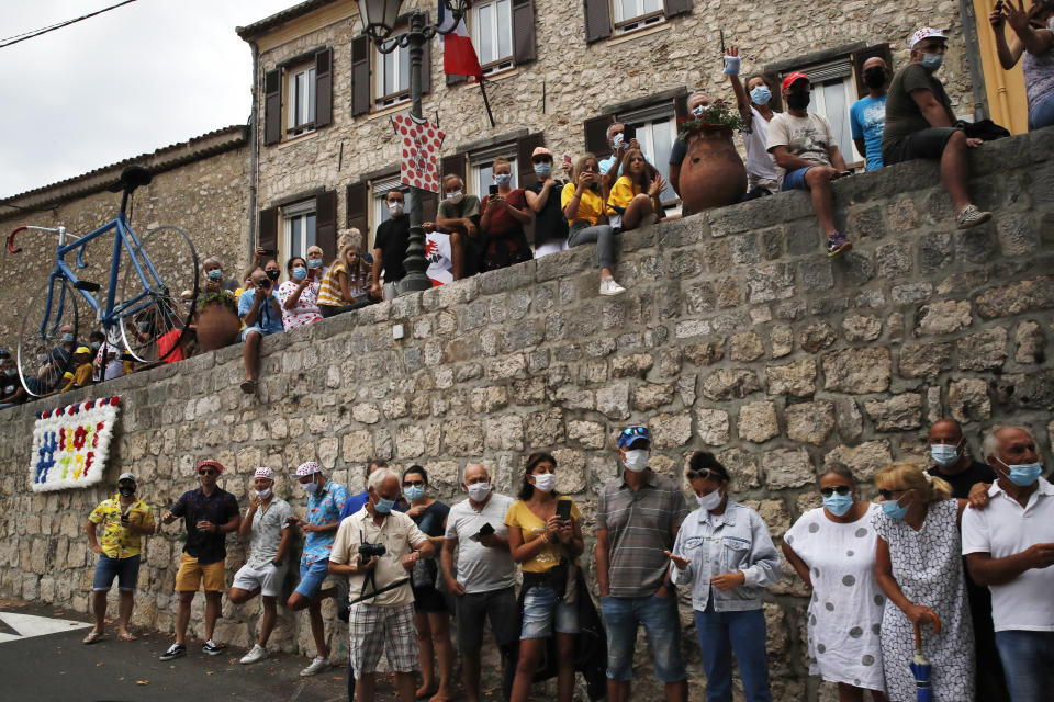 People wearing face masks wait for the riders to pass during the first stage of the Tour de France cycling race over 156 kilometers (97 miles) with start and finish in Nice, southern France, Saturday, Aug. 29, 2020. (AP Photo/Christophe Ena)