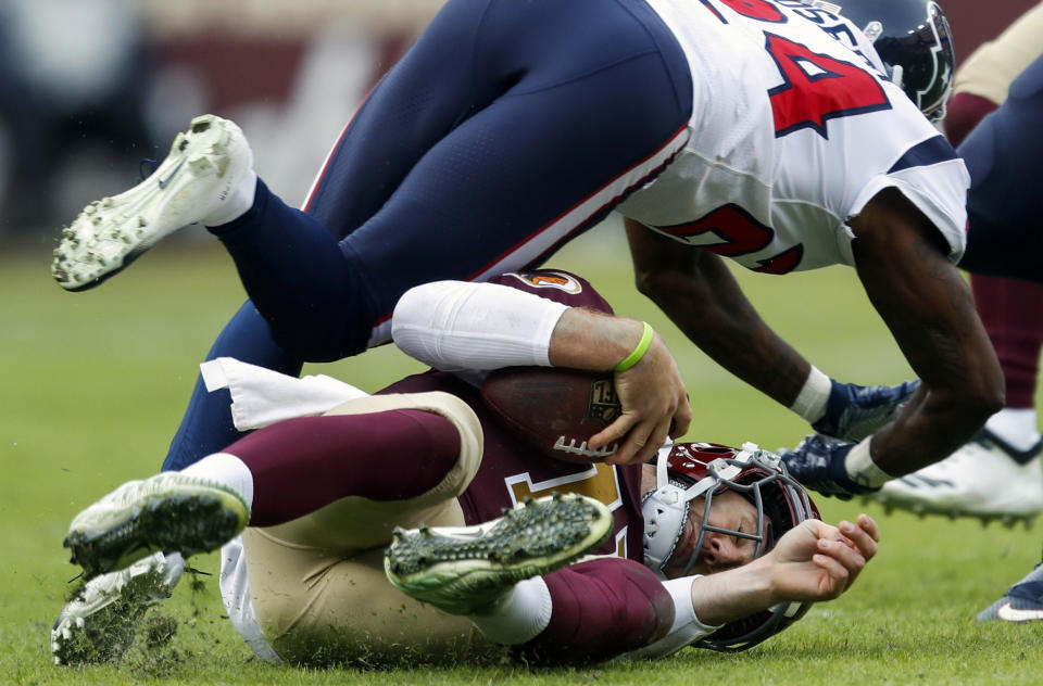 Washington Redskins quarterback Alex Smith, bottom, slides under Houston Texans cornerback Johnathan Joseph (24) during the first half of an NFL football game, Sunday, Nov. 18, 2018, in Landover, Md. (AP Photo/Pablo Martinez Monsivais)