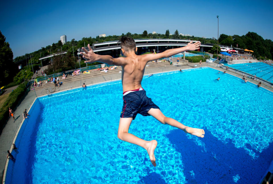 07 June 2018, Germany, Hanover: A youth jumps from a diving tower at the Lister Freibad open air swimming pool. (Photo taken using fish-eye lens) Photo: Hauke-Christian Dittrich/dpa (Photo by Hauke-Christian Dittrich/picture alliance via Getty Images)