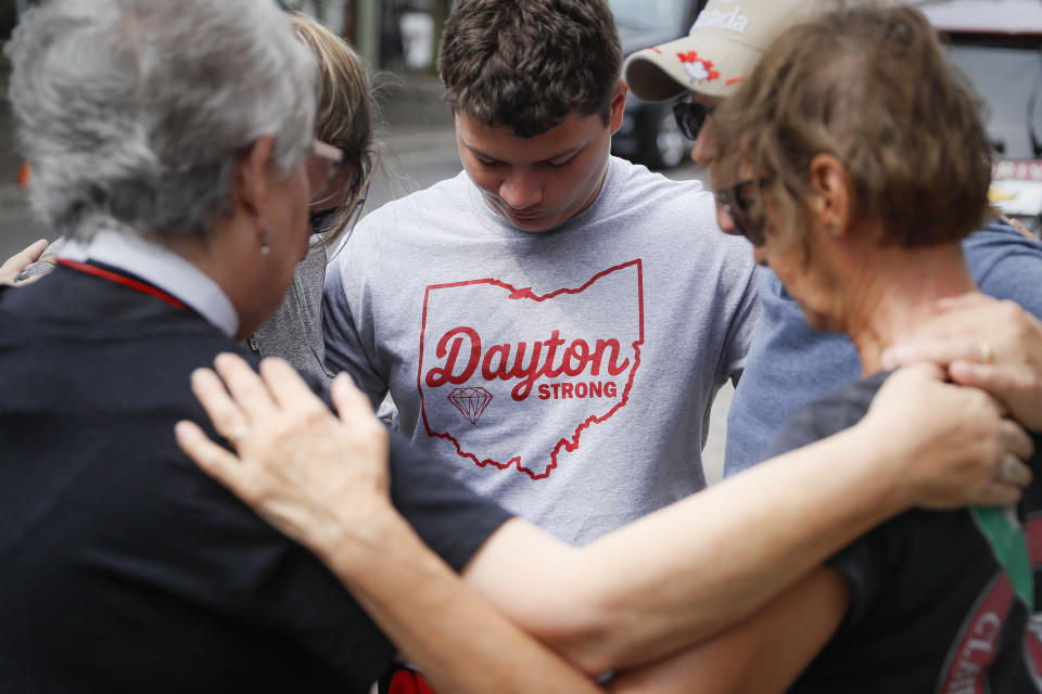 Mourners gather and share a pray near a makeshift memorial Tuesday, Aug. 6, 2019, for the slain and injured in the Oregon District after a mass shooting that occurred early Sunday morning, in Dayton. (AP Photo/John Minchillo)