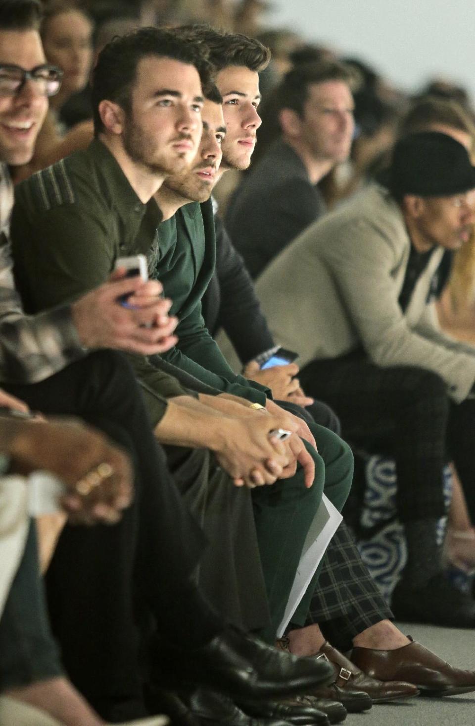 The Jonas Brothers, from left, Kevin, Joe and Nick, watch the Richard Chai Spring Summer 2014 collection on Thursday, Sept. 5, 2013 during Fashion Week in New York. (AP Photo/Bebeto Matthews)