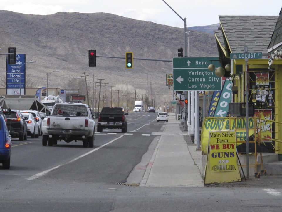 Traffic passes on Main Street in Fernley, Nev. about 30 miles east of Reno Thursday, March 18, 2021, The town founded a century ago by pioneers lured to the West with the promise of free land and cheap water is suing the U.S. government over plans to renovate an earthen irrigation canal that burst and flooded nearly 600 homes in Fernley in 2008. (AP Photo/Scott Sonner).