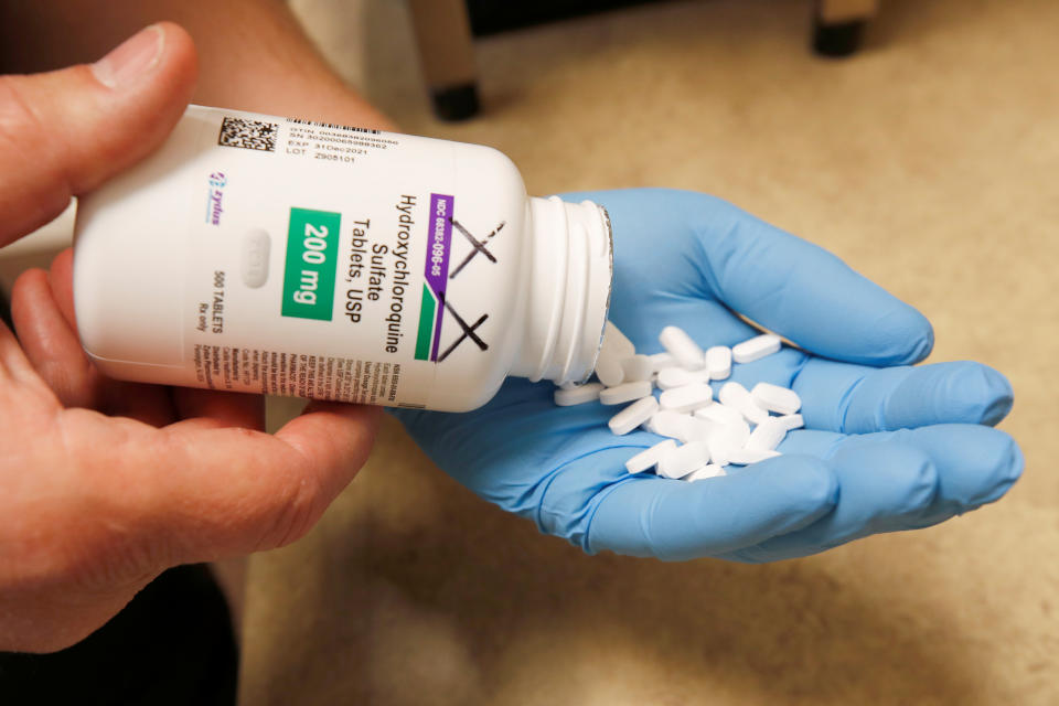 The drug hydroxychloroquine being poured from a pill container into a gloved hand