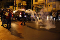 Protesters are seen surrounded by tear gas that was fired towards them by Lebanese riot police during an anti-government protest in Beirut, Lebanon, Wednesday, Dec. 4, 2019. Protesters have been holding demonstrations since Oct. 17 demanding an end to corruption and mismanagement by the political elite that has ruled the country for three decades. (AP Photo/Bilal Hussein)