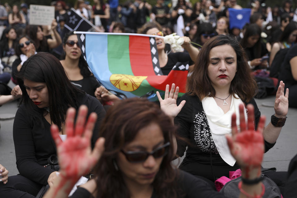 Women sit in front of La Moneda presidential palace during a march against President Sebastian Pinera in Santiago, Chile, Friday, Nov. 1, 2019. Groups of Chileans continued to protests as government and opposition leaders debated the response to nearly two weeks of protests that have paralyzed much of the capital and forced the cancellation of two major international summits. (AP Photo/Rodrigo Abd)