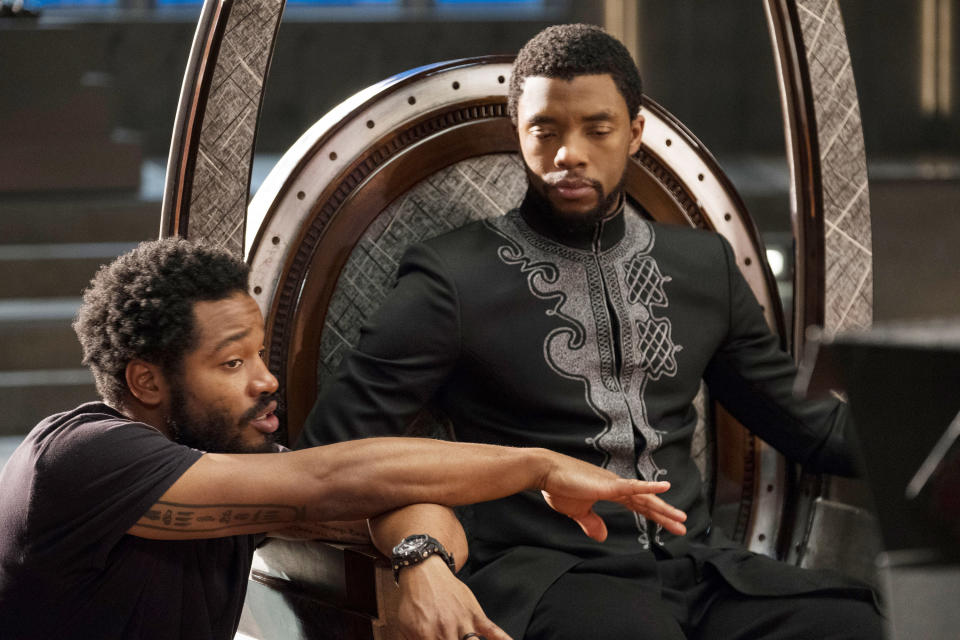 Chadwick sitting on the throne as Ryan is crouched next to him discussing a scene during filming