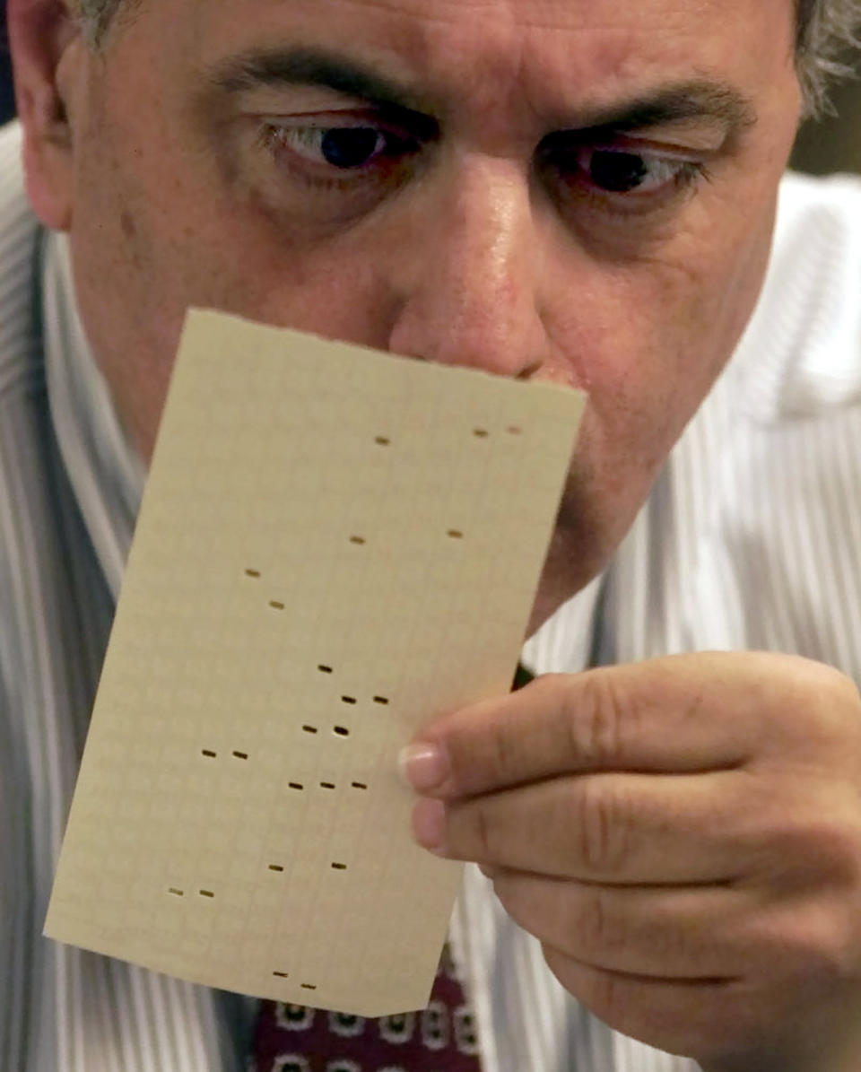 FILE- In this Nov. 22, 2000 file photo, Broward County, Fla. canvassing board member Judge Robert Rosenberg examines a challenged vote at the Broward County Emergency Operations Center in Plantation, Fla. The 2000 presidential election was decided in Florida by 537 votes after the U.S. Supreme Court halted recounts. The election increased rancor between the two major parties and highlighted deficiencies in the nation's voting infrastructure. (AP Photo/Wilfredo Lee, File)